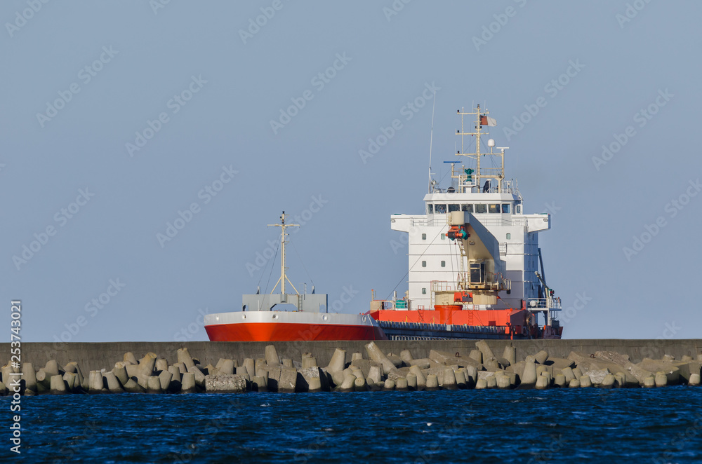 RED CARGO VESSEL - Merchant ship is sailing along waterway to the port of Swinoujscie RED CARGO VESSEL - Merchant ship is sailing along waterway to the port of Swinoujscie