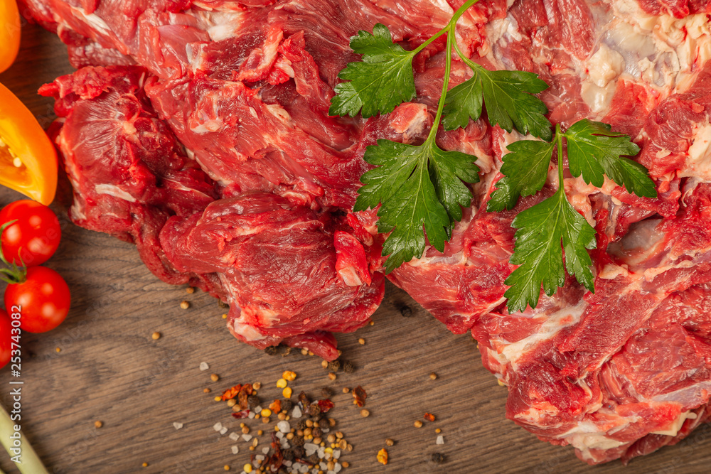 Raw beef on a wooden background with spices and vegetables. Raw beef on a wooden background with spices and vegetables.