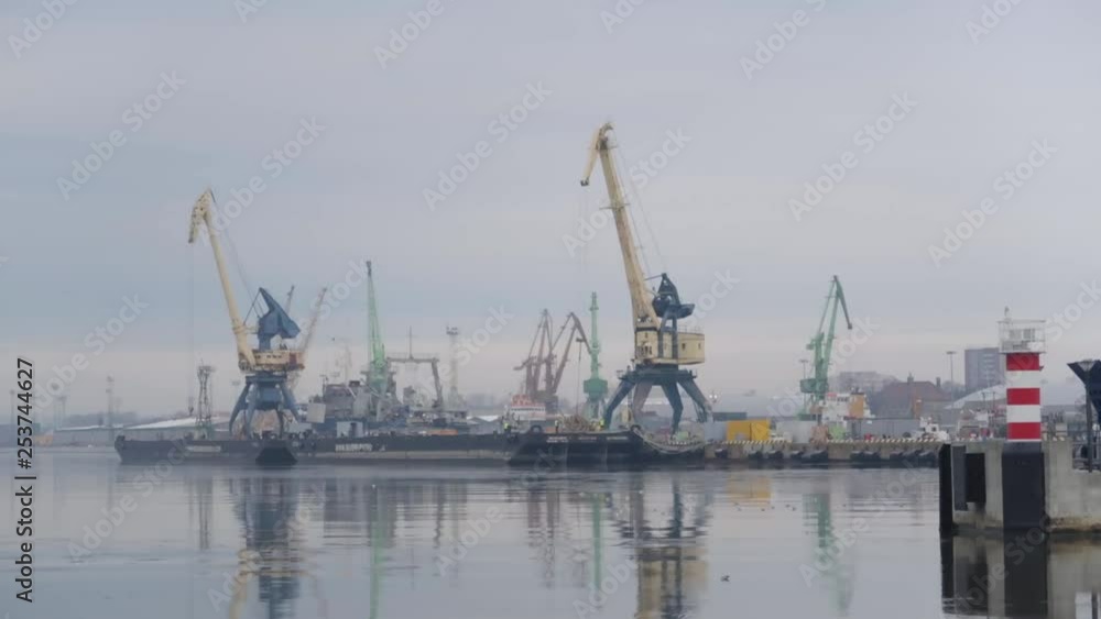 industrial port seen from distance with tall cranes and icy cold water with moody cloudy sky industrial port seen from distance with tall cranes and icy cold water with moody cloudy sky