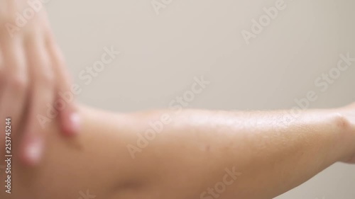A close-up of a young woman rubs natural oil cosmetic product into the skin of her hands with gentle movements
