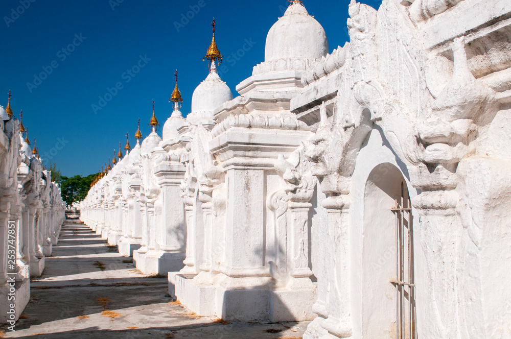 Kuthodaw Pagoda contains the worlds biggest book. There are 729 white stupas with caves with a marble slab inside page with buddhist inscription. Mandalay, Myanmar.