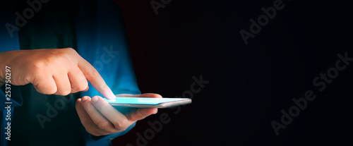 Close up business man formal blue suit Use hold smart phone in the dark.
