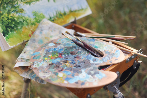 Palette and easel with brushes in nature