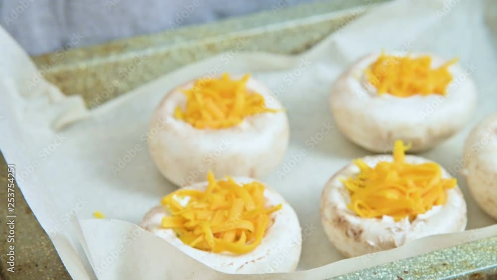 Close-up of female hands spreading mushrooms stuffed with cheese on a baking sheet while cooking Close-up of female hands spreading mushrooms stuffed with cheese on a baking sheet while cooking