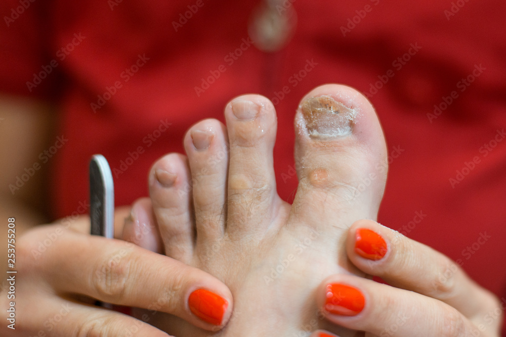 Naklejka premium Male pedicure. A pedicure master with gloves holding a man’s foot.