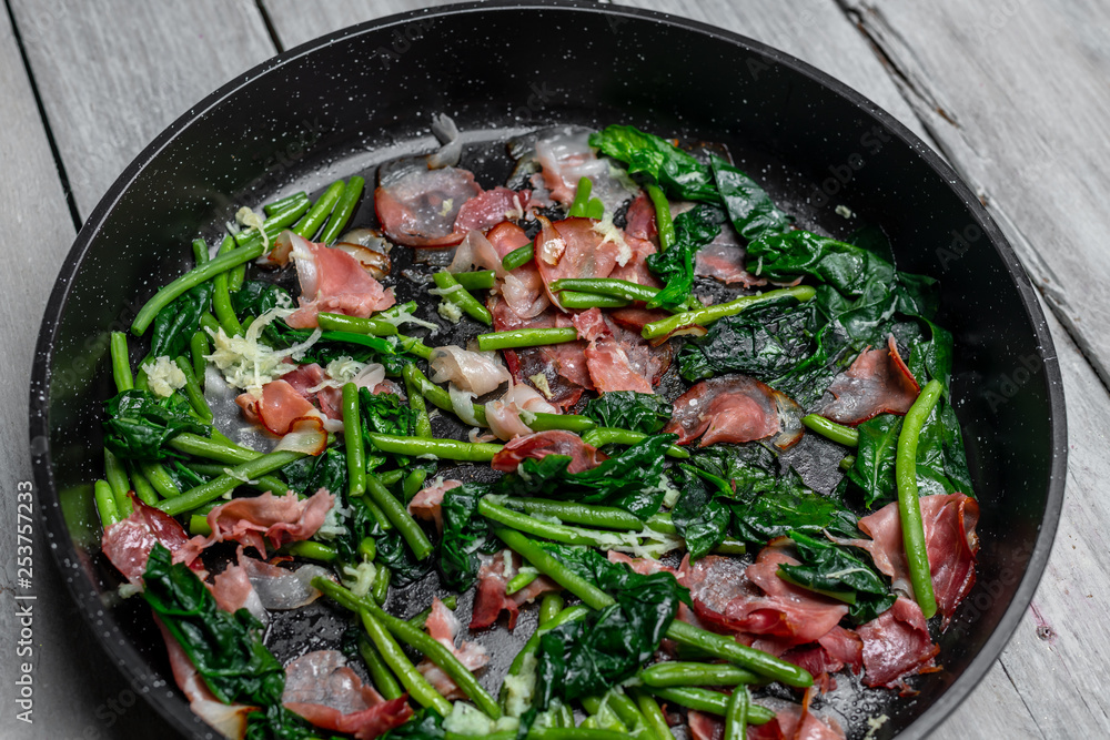Peas sprouts, young spinach leaves fried in a pan together with a crispy, bacon-flavored Peas sprouts, young spinach leaves fried in a pan together with a crispy, bacon-flavored