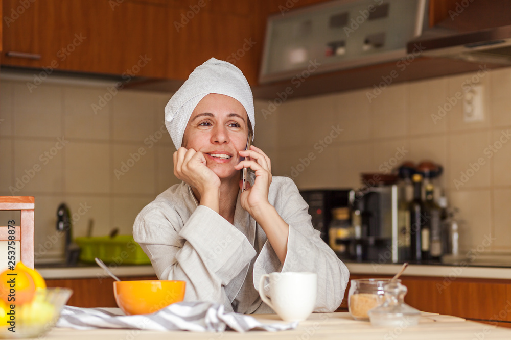 Beautiful mid adult woman using smart phone in kitchen Beautiful mid adult woman using smart phone in kitchen