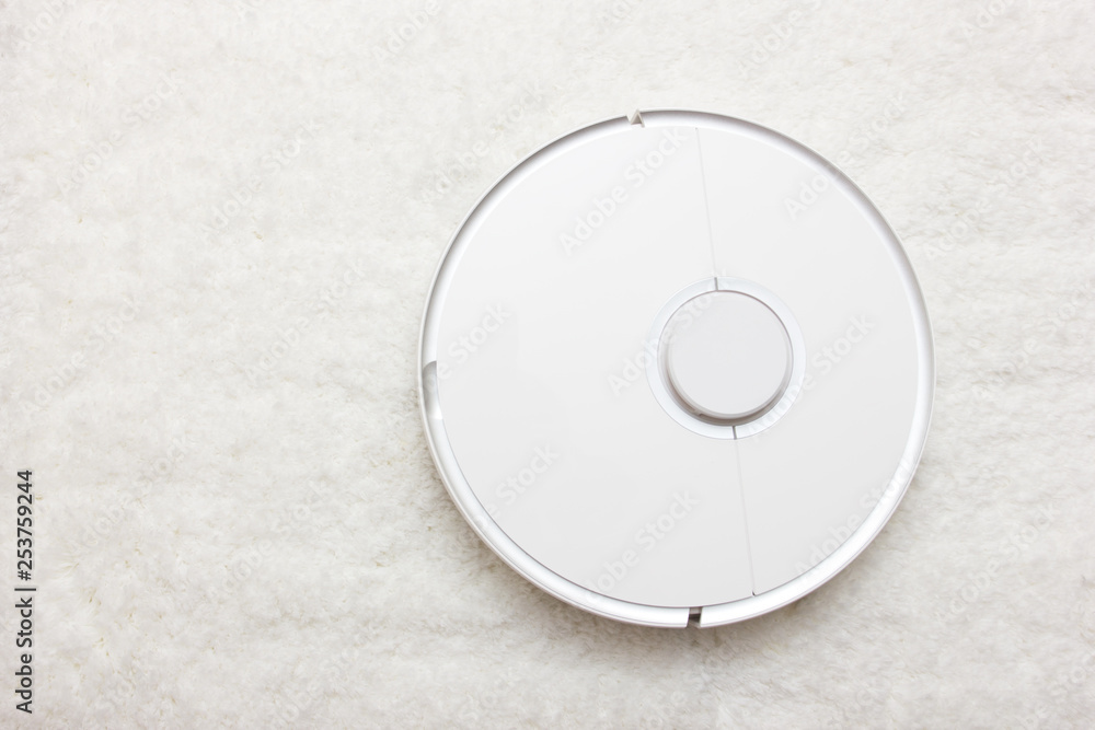 Automation cleaning. White robot vacuum cleaner collects dust, hair on the carpet