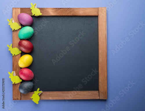 Blackboard and colorful Easter eggs around it. View from above.