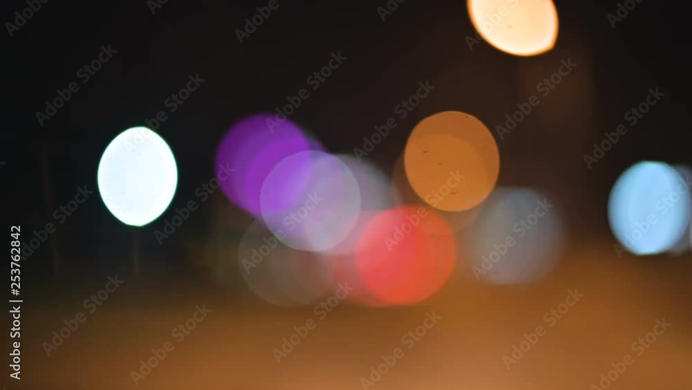 Colored bokeh lights in the night city. moving circles of traffic lights lights signs. Defocused night highlights on city road Colored bokeh lights in the night city. moving circles of traffic lights lights signs. Defocused night highlights on city road