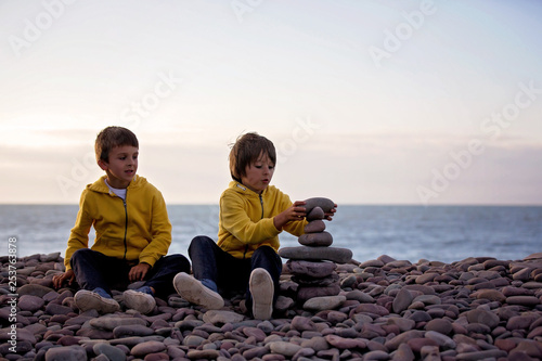 Children, playing on a rocky beach, throwing stones
