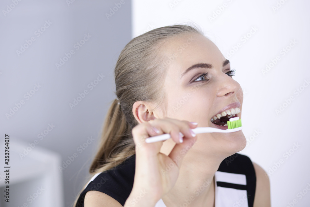 Smiling young woman with healthy teeth brushing her teeth Smiling young woman with healthy teeth brushing her teeth