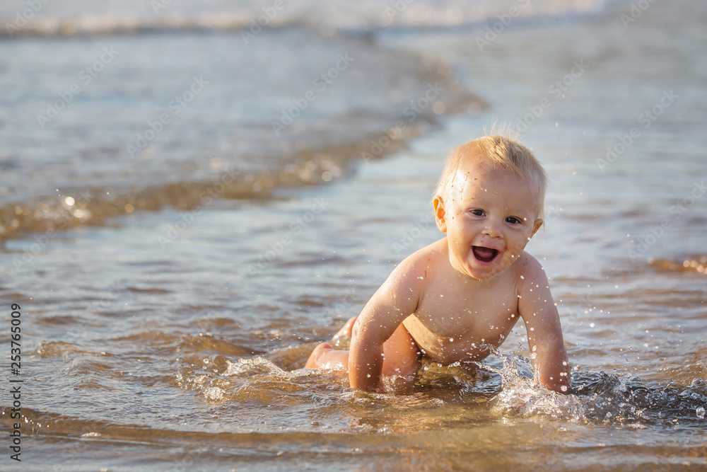 Baby boy, playing on the beach in the water, smiling Baby boy, playing on the beach in the water, smiling