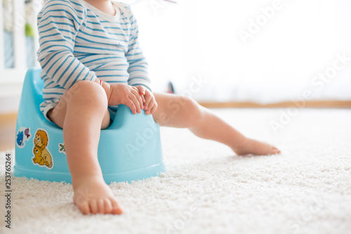 Cute toddler boy, potty training, playing with his teddy bear