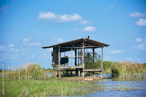 An old house in the green field and blue sky background at the Talae Noi, Phatthalung province, Thailand © Teeradej