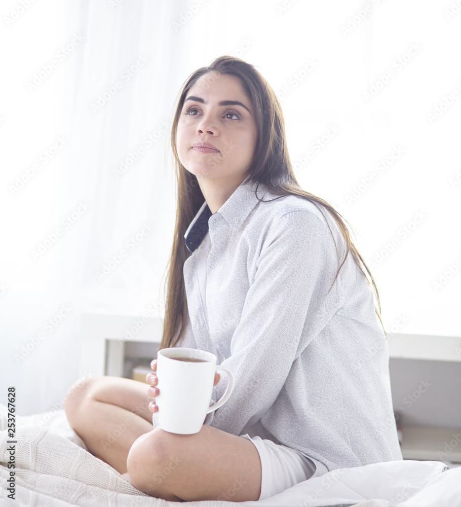 Young beautiful happy brunette woman in black silk dressing gown lying in bed, drinking morning coffee, white cup. Womens day holiday Young beautiful happy brunette woman in black silk dressing gown lying in bed, drinking morning coffee, white cup. Womens day holiday