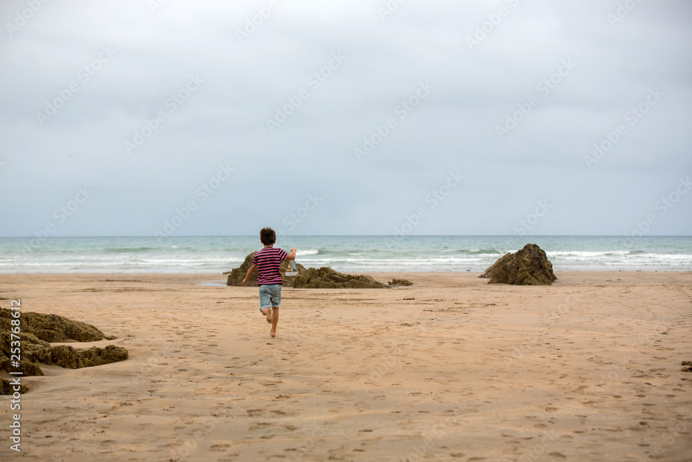 Child plays with sand on beach. Cute preschool boy with toy ship on beach. Stormy seaside sgore and kid playing Child plays with sand on beach. Cute preschool boy with toy ship on beach. Stormy seaside sgore and kid playing