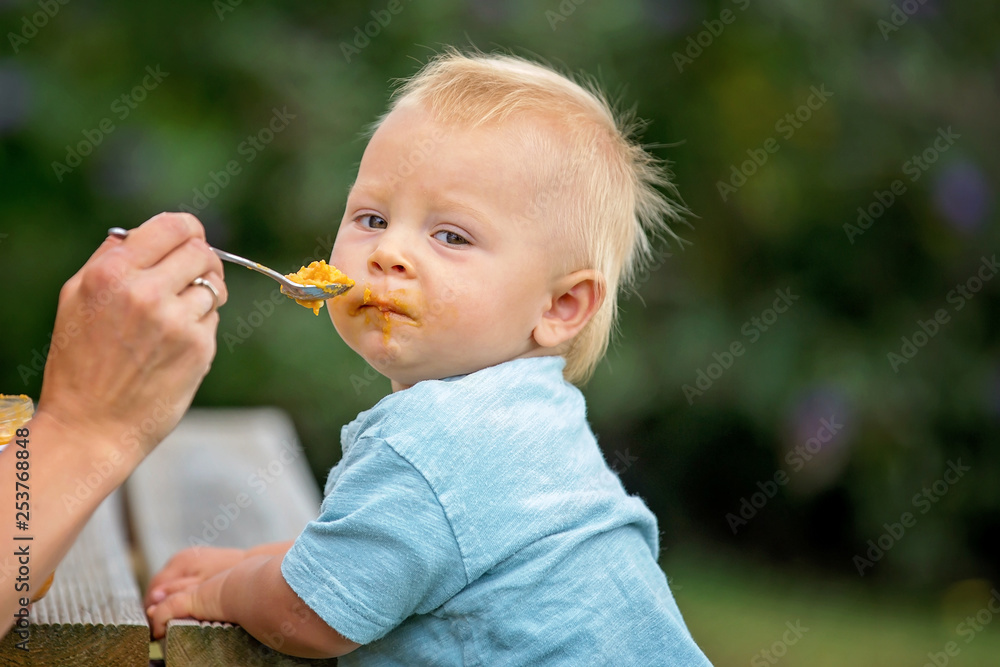 Mother, feeding her baby boy outdoor in the park Mother, feeding her baby boy outdoor in the park