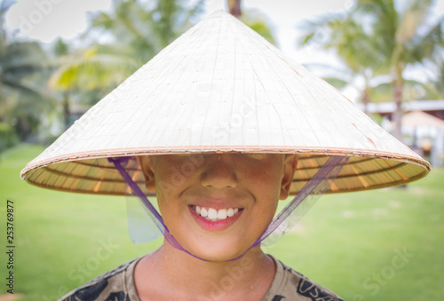 Happy asian with Chinese New Year greetings wearing vietnamese hat and smiling, no eyes are visible photo