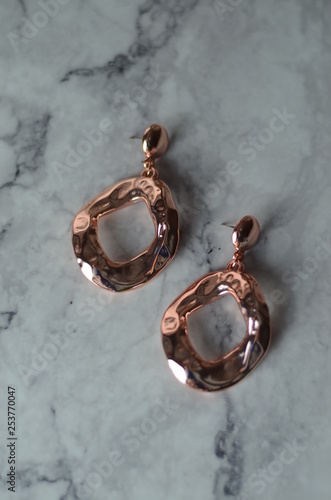 Rose gold earrings on marble table