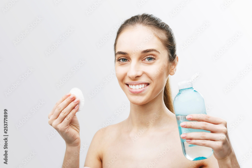 Brunette woman holding micellar water and cotton pad after make up removing Brunette woman holding micellar water and cotton pad after make up removing
