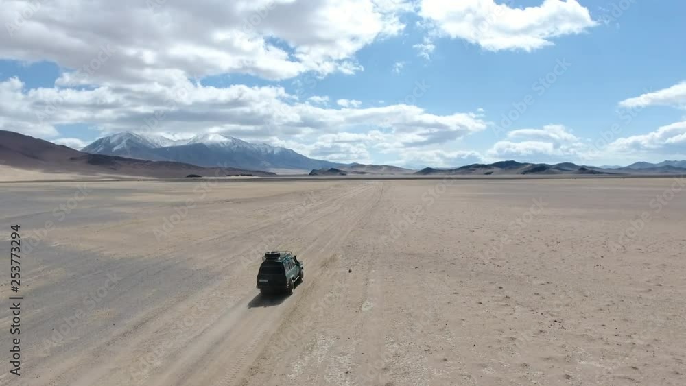 Aerial view of an old offroad car driving in the desert of Mongolia Aerial view of an old offroad car driving in the desert of Mongolia