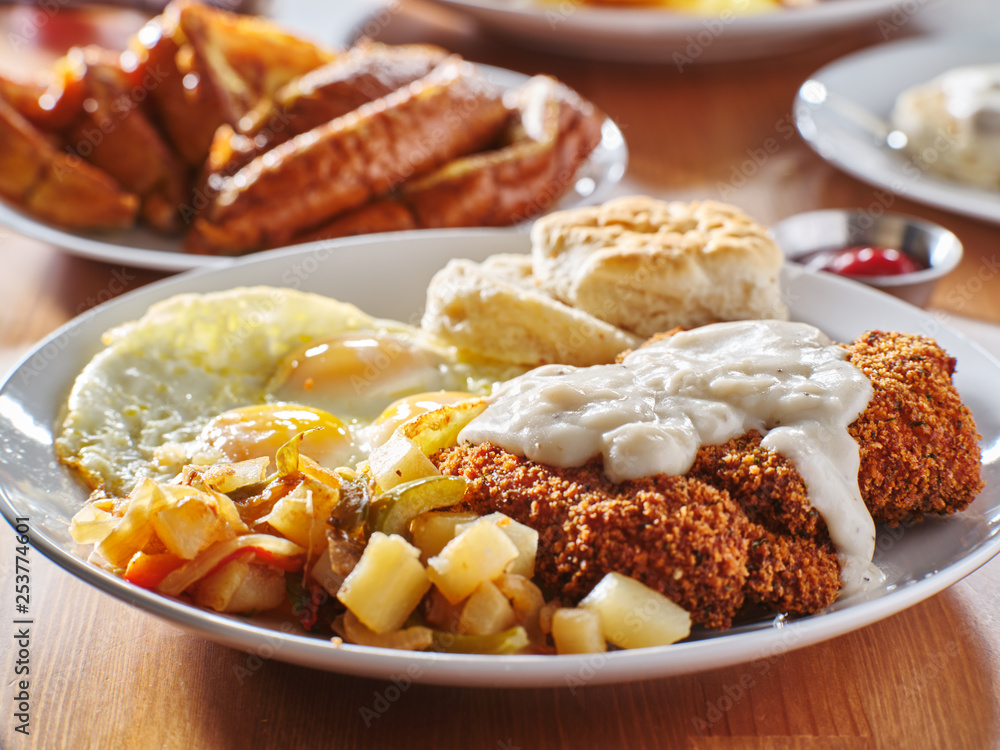 chicken fried steak covered in gravy with sunny side up eggs and breakfast foods chicken fried steak covered in gravy with sunny side up eggs and breakfast foods