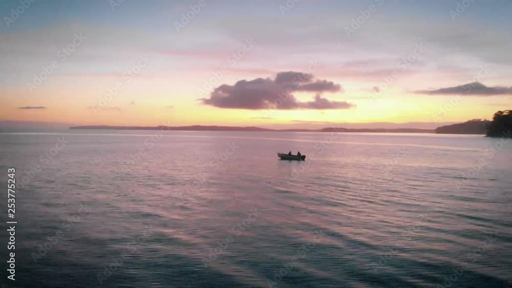 Row boat out at sea during sunset in New Zealand