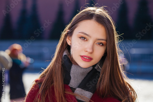 Young beautiful brunette woman in red coat posing on winter park