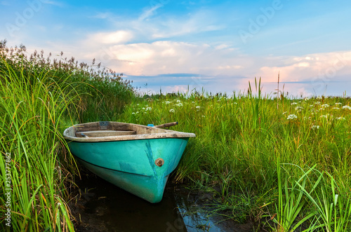 Old plastic fishing boat on the bank of river