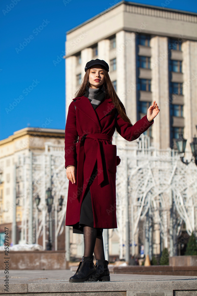 Beautiful girl in stylish in a long burgundy coat