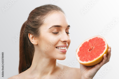 Young lady with brunette hair inhales the scent of grapefruit