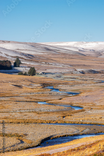 Pont Ar Elan, Elan valley, wales. Snowy scene of Afon elan river winding through the mountain landscape with farm building in the distance