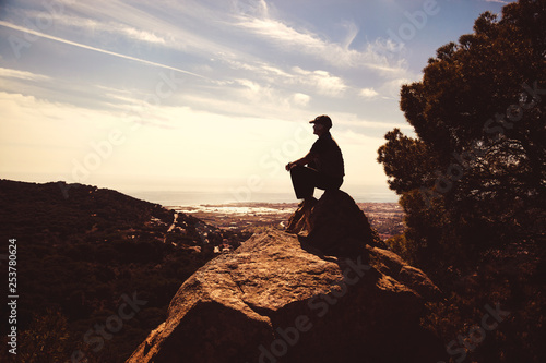 Hiker sitting on a rock with great view, side view