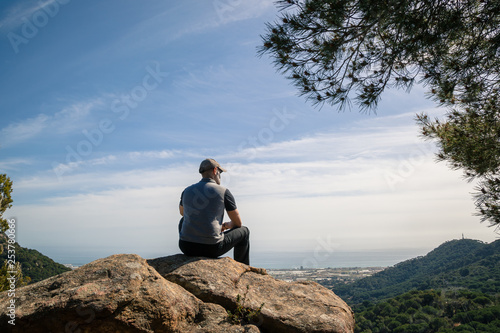 Hiker sitting on a rock with great view, back view