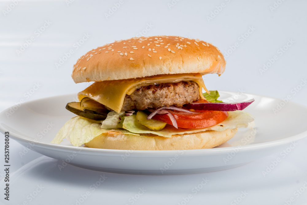 cheeseburger with beef cutlet, bacon, tomatoes and cheese slices, seasoned with sauce and green salad for a restaurant menu on a white isolated background cheeseburger with beef cutlet, bacon, tomatoes and cheese slices, seasoned with sauce and green salad for a restaurant menu on a white isolated background
