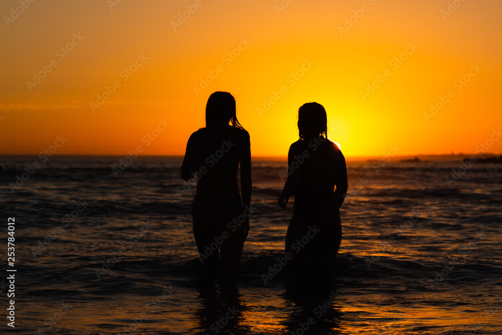 Two girls stand in the ocean