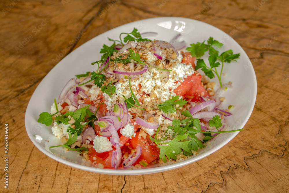 Salad with peeled tomatoes cut into cubes, cow cheese, walnuts, red onion and fresh green spices. Salad with peeled tomatoes cut into cubes, cow cheese, walnuts, red onion and fresh green spices.