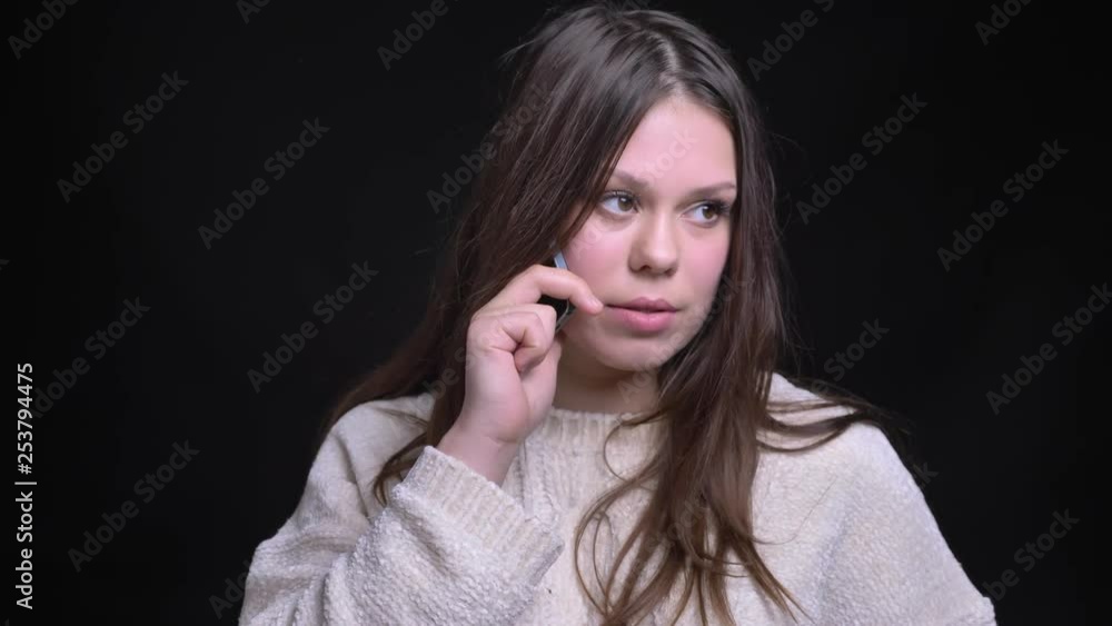 Closeup shoot of young pretty caucasian female having a casual conversation on the phone in front of the camera Closeup shoot of young pretty caucasian female having a casual conversation on the phone in front of the camera