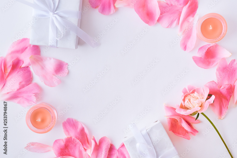 Flat lay composition with pink petals and gift boxes on a white background