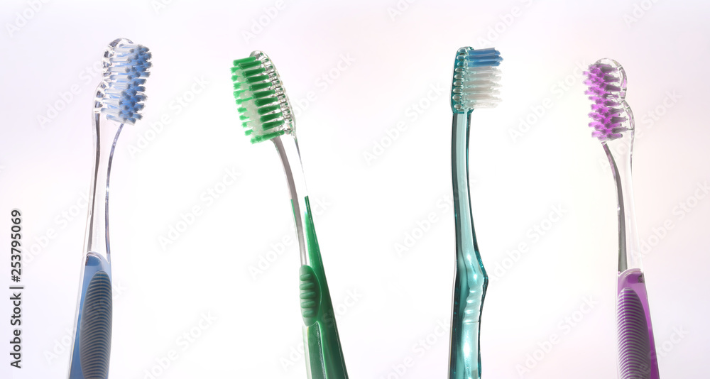 Four colorful transparent tooth brushes on pink gradient Four colorful transparent tooth brushes on pink gradient