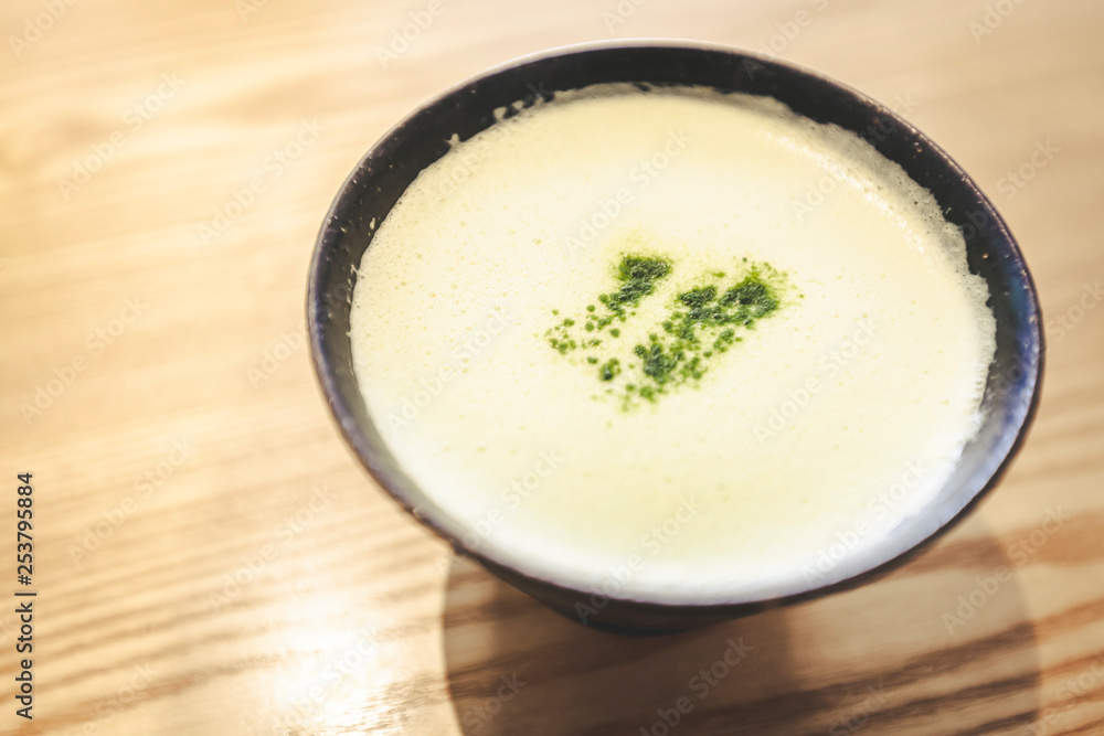 Close up of fresh brewed matcha latte with Japanese matcha green tea powder in black cup and stylish wooden table Close up of fresh brewed matcha latte with Japanese matcha green tea powder in black cup and stylish wooden table