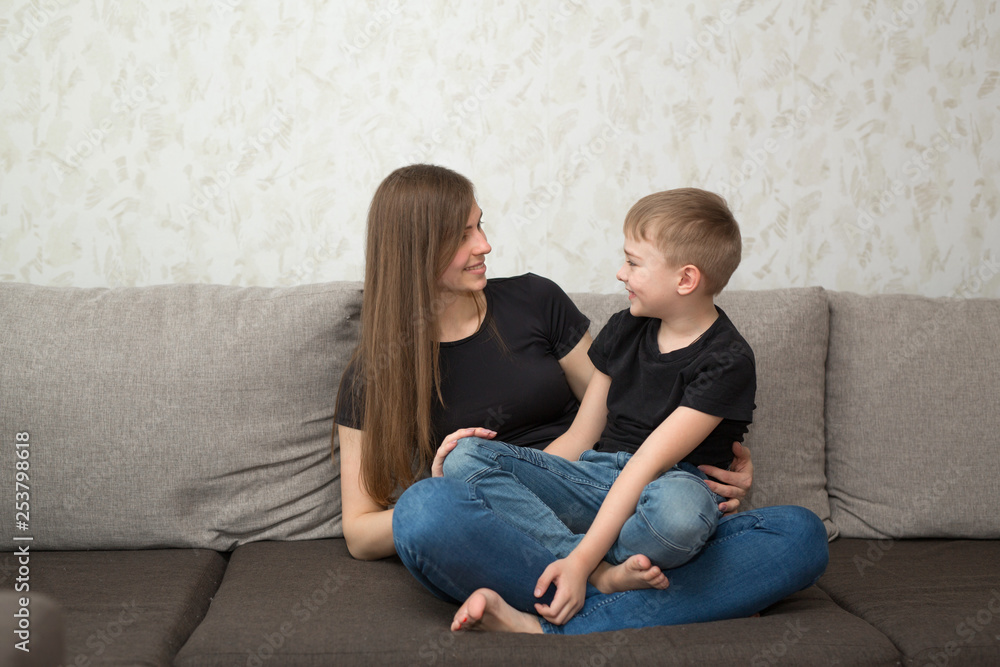 beautiful young mother with her son on the couch in the home interior