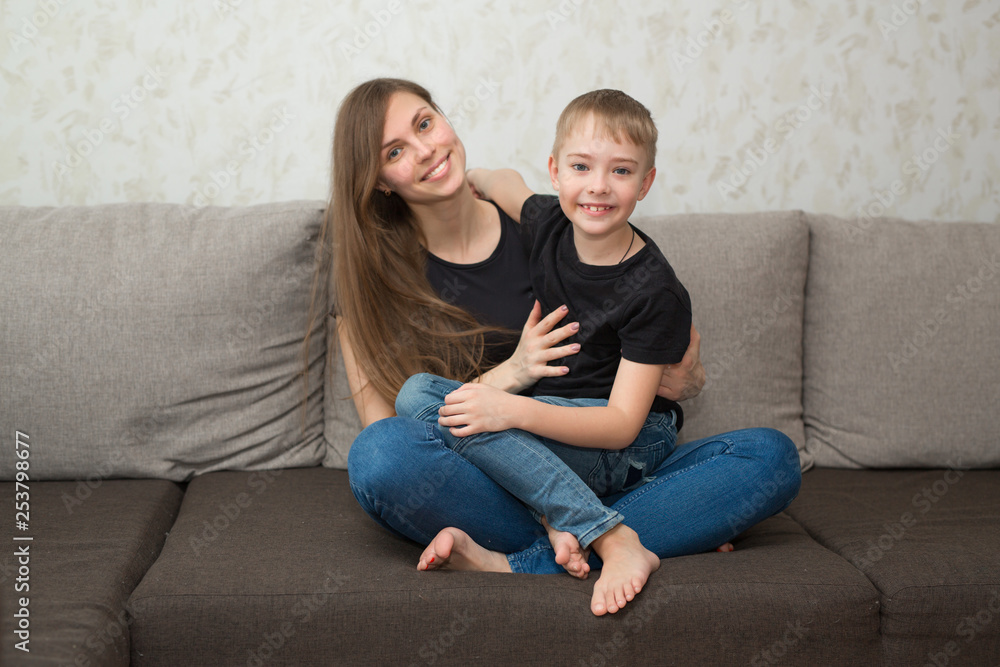 beautiful young mother with her son on the couch in the home interior