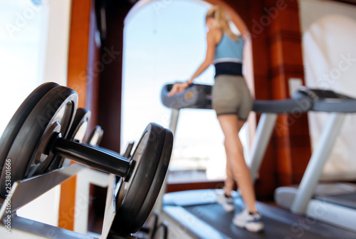 girl on the morning run on the treadmill in the gym in front of a large window on the background of the sea