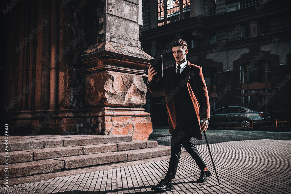 Fashion portrait of young man on red coat, white shirt, black suit and cane  walking on streets of city background. Model shooting Stock Photo | Adobe  Stock