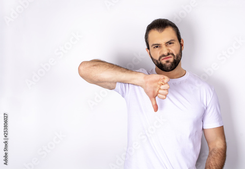 handsome man in white t-shirt over white background showing dislike