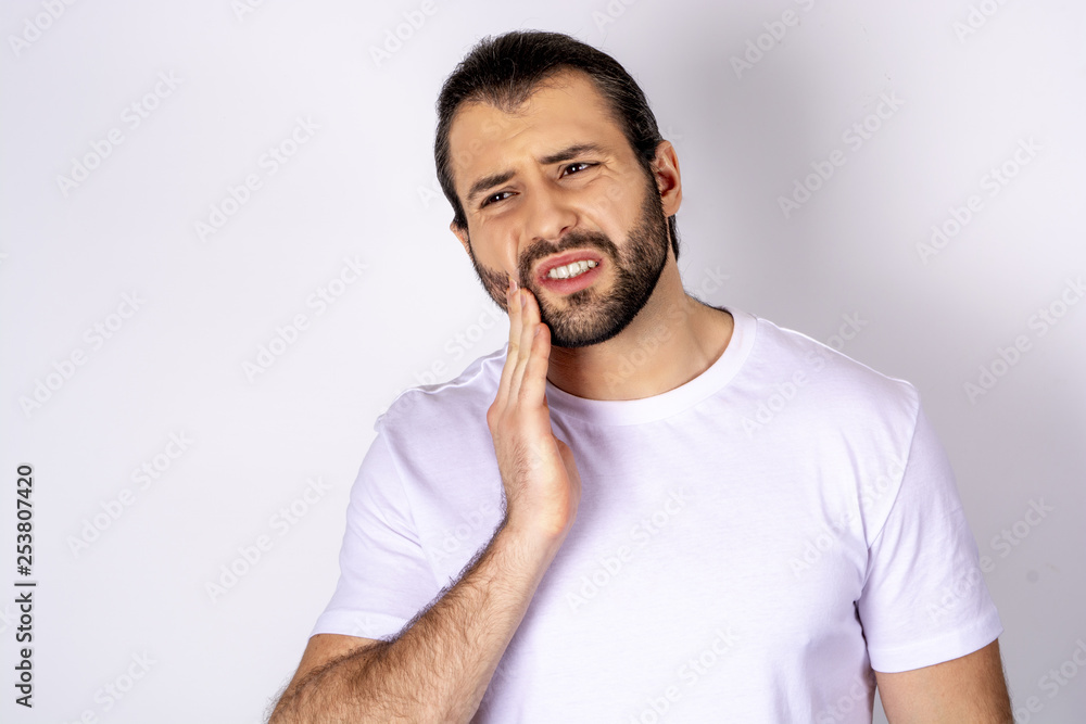 Handsome man in a white T-shirt on a white background, toothache Handsome man in a white T-shirt on a white background, toothache
