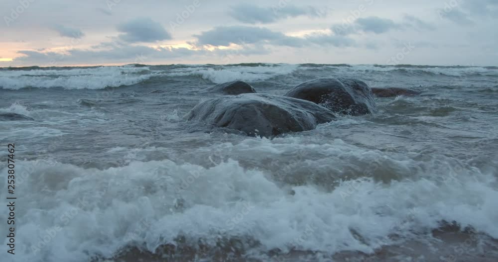 Storm waves crashing to rocks on beach at sunset Storm waves crashing to rocks on beach at sunset