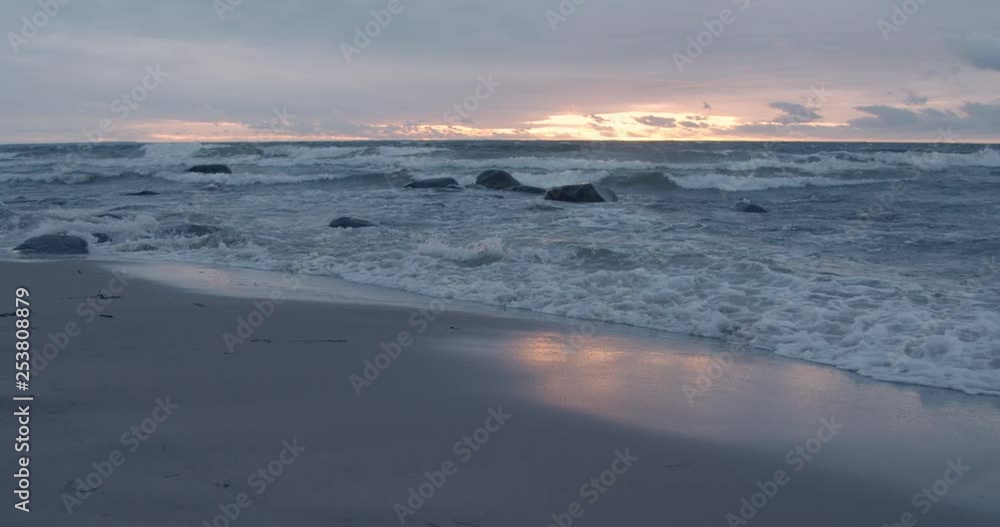 Waves on sandy beach on coast at sunset